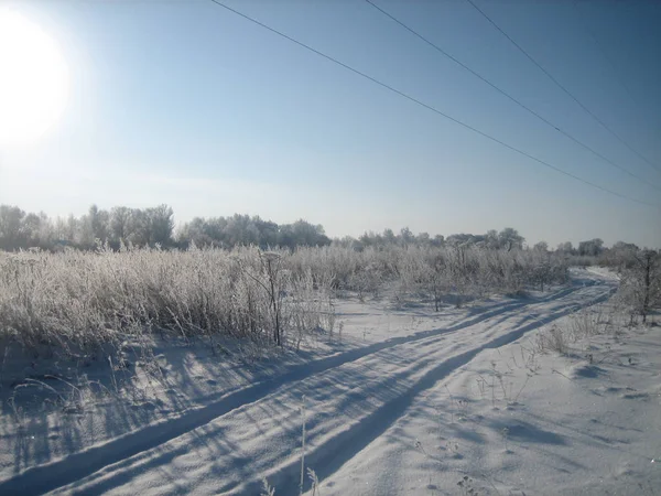 在晴朗的霜冻日，在干净的平坦田野上的冬季道路. — 图库照片