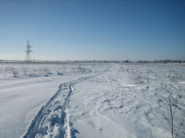 Camino de invierno en un campo plano limpio en un día despejado y helado . — Foto de Stock