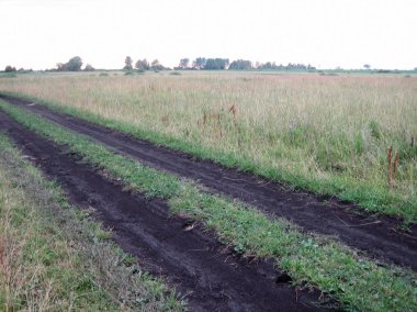 Bir altında günün sonunda çim düz bir alanda Kir yol