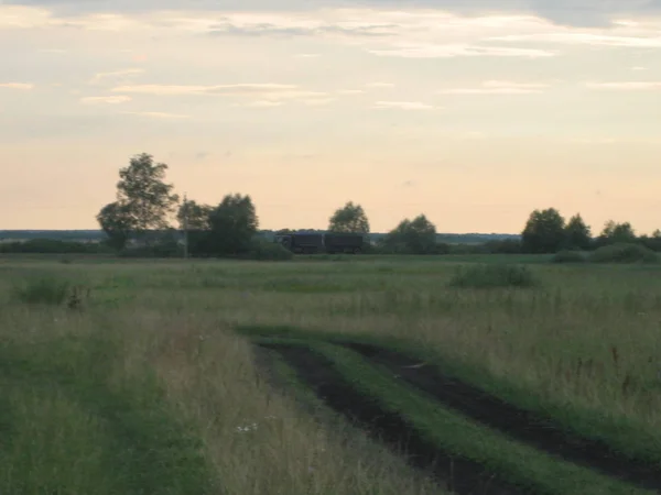 Strada sterrata nel campo al tramonto di una giornata estiva. Alto, non rifilato — Foto Stock