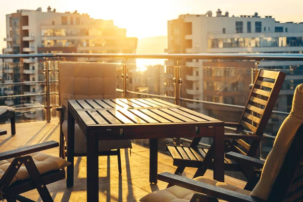 Outdoor Terrace With Garden Furniture In The Background Of The City And Sunset. Luxury Apartments Resort Recreation Summer Concept