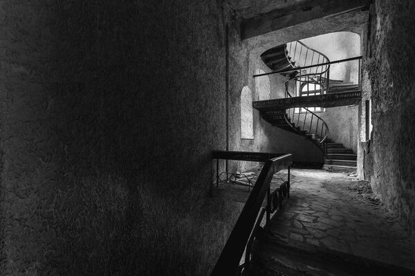 The circular staircase with steps in an abandoned house with copy-space, black and white image. The concept of the modern loft.
