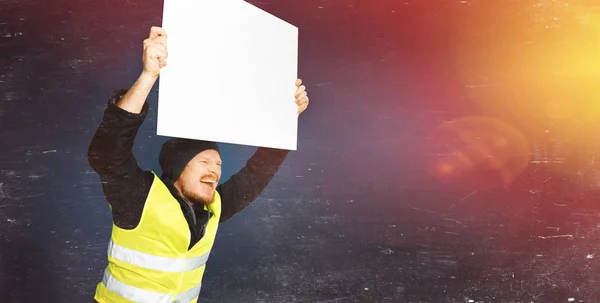 Protests yellow vests. Young worker is holding a poster with lights. The concept of revolution and protest, the struggle for equal rights, the electoral movement