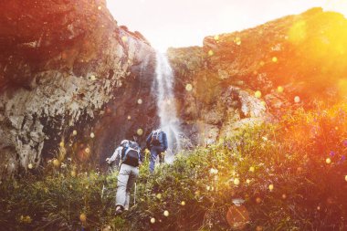 Turist grubu, yürüyüş yokuş yukarı için şelale güneş ışığı ile. Seyahat macera açık kavramı