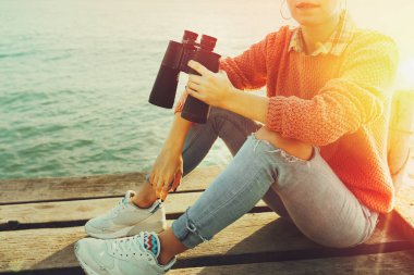 Tanınmayan kız kot bir iskele dürbün ile el seyahat kavramı oturur