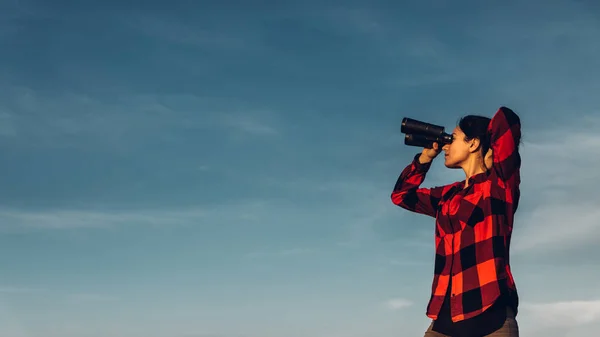 Hermosa joven viajero mira a través de prismáticos contra un — Foto de Stock