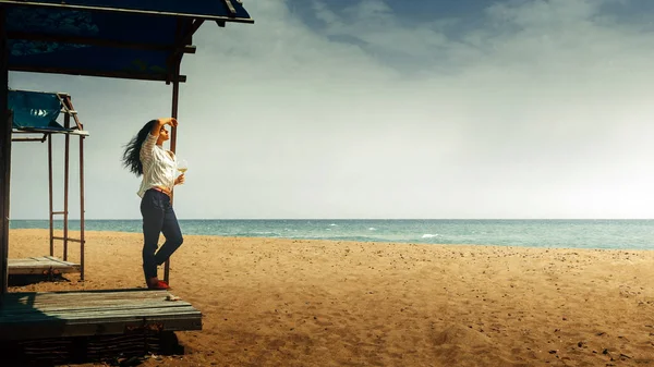 Hermosa joven con una copa de vino se para en la playa y disfruta del hermoso paisaje. Concepto de felicidad de salud vacacional — Foto de Stock