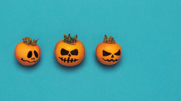 Halloween concept. Drie enge pompoenen op een azuurblauwe achtergrond met ruimte voor tekst, platte stijl — Stockfoto