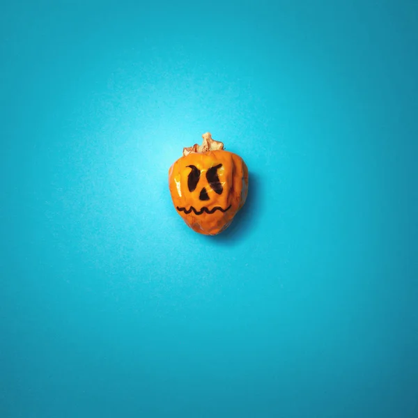 Halloween minimalisme concept. Enge vakantie pompoen op azuurblauwe achtergrond, bovenaanzicht plat lay — Stockfoto