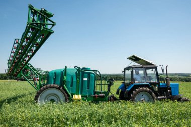 mavi gökyüzü ile alanındaki mavi traktör bitki püskürtme ve kimyasal tedavi için hazırlanıyor