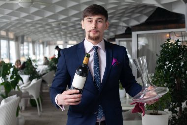 Genç erkek sommelier kırmızı şarap tadımı sırasında bir sürahi dökme