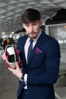 Genç erkek sommelier şarap tadımı restoranda sırasında bir şişe kırmızı şarap tutar