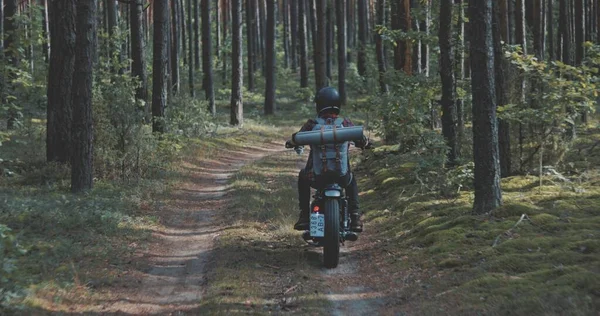 Jonge renner rijdt motorfiets op bosweg — Stockfoto