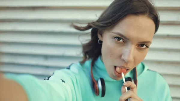 Girl licking lollipop and making selfie using smartfone — Stock Photo, Image