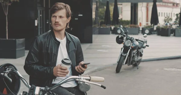 Biker drinken van koffie tijdens het staan in de buurt van motorfiets — Stockfoto