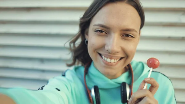 Menina lambendo pirulito e fazendo selfie usando smartfone — Fotografia de Stock