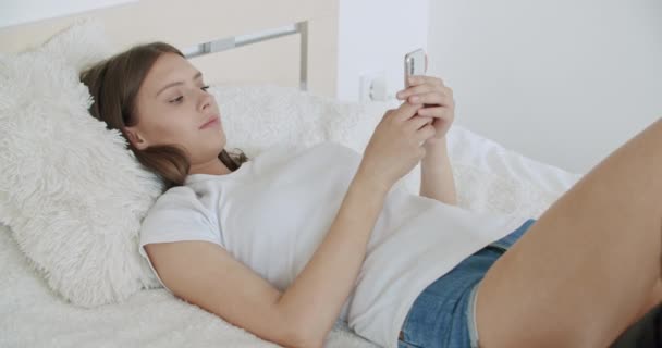 Девушка, лежащая на кровати дома — стоковое видео