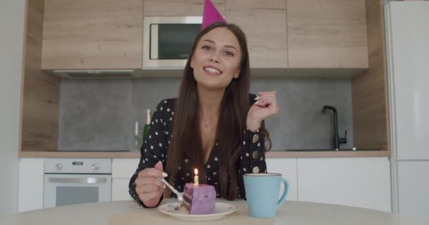 Жінка у вечірній шапці запалює свічку на торт — стокове відео
