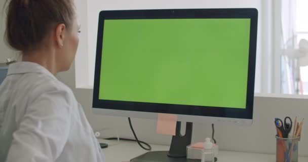 Доктор працює на комп'ютері з зеленим маком екрану — стокове відео