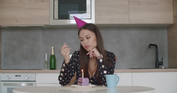 Nő party sapkában gyertyát gyújt egy tortán — Stock videók