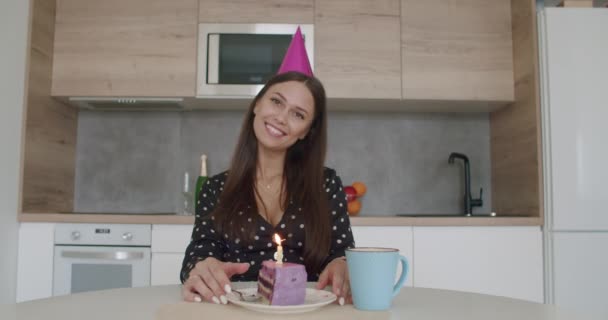 Nő party sapkában gyertyát gyújt egy tortán — Stock videók