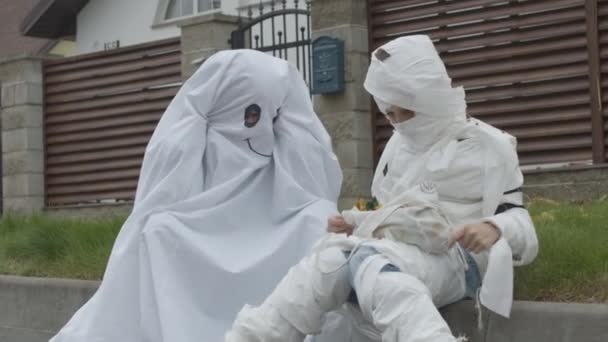 Children in mummy and ghost costumes share candy — Stock Video