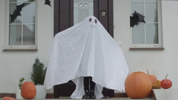 Girl in ghost costume holds pumpkin in her hands — Stock Video