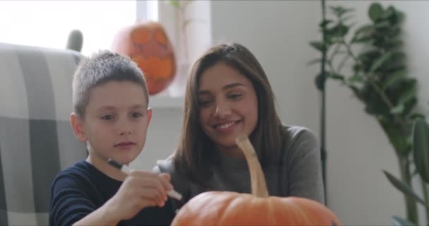 Kvinna med son måla pumpa för Halloween — Stockvideo