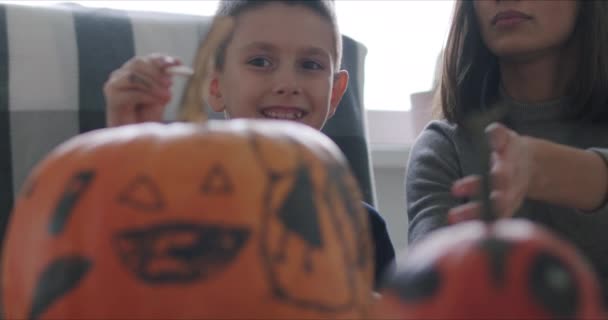 Vrouw met zoon verf pompoen voor Halloween — Stockvideo