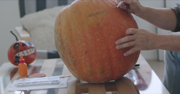 Mannelijke handen snijden gaten in pompoen — Stockvideo