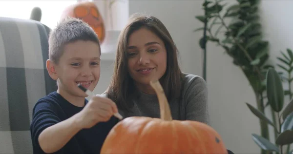 Mujer con hijo pintar calabaza para Halloween —  Fotos de Stock