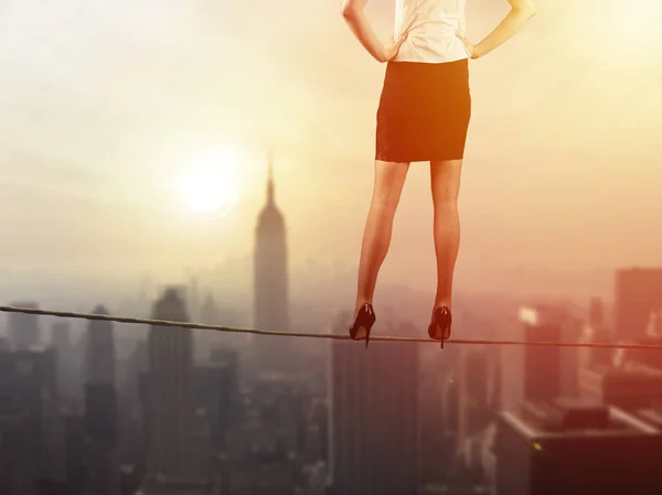 Work life balance employment concept: Business woman balancing on the rope high above the city