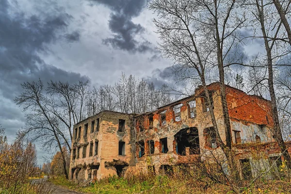 Velho edifício de tijolo abandonado no fundo de um céu de outono chuvoso — Fotografia de Stock