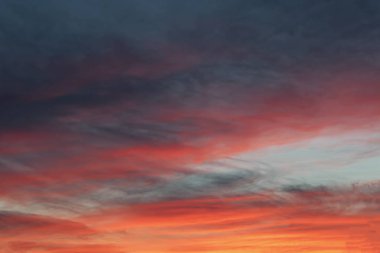 Bulutlar gökyüzünde Güneşin ufukta ayarlama ışınları tarafından aydınlatılmış