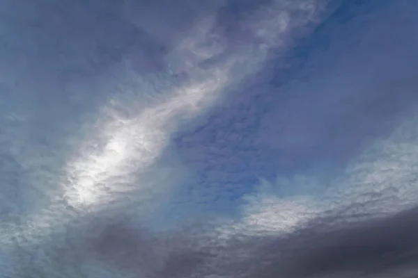 青い空に羽のような雲が地平線に夕日の光に照らされています — ストック写真