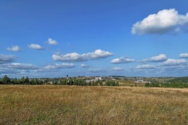 Güneşli bir yaz yılında haystacks ile kırsal manzara. Kırsal manzara mavi gökyüzünde bulutlar ile.