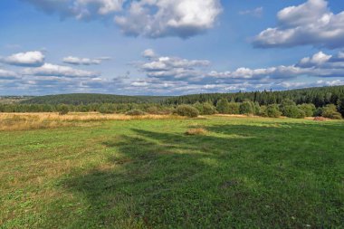 Güneşli bir yaz yılında haystacks ile kırsal manzara. Kırsal manzara mavi gökyüzünde bulutlar ile.