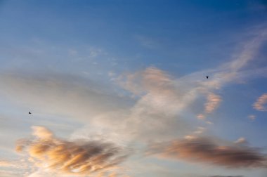 mavi gök tüylü bulutlarda ayarlama ufukta güneş ışınlarının tarafından aydınlatılmış
