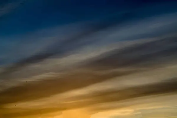 Langit biru dengan awan emas Matahari terbenam dramatis, latar belakang alam yang indah. Mengatur matahari menerangi awan . — Stok Foto