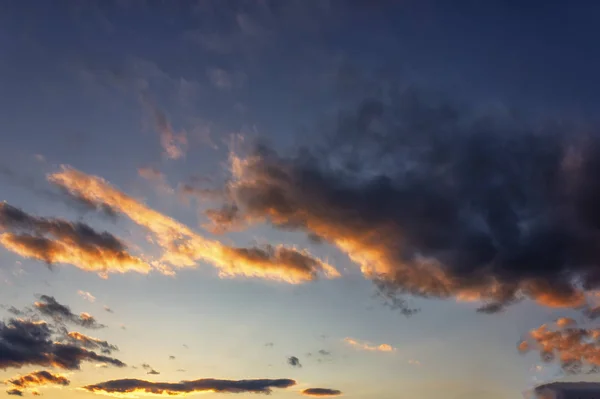 Cielo azul con nubes de oro - puesta de sol dramática, hermoso fondo natural. El sol poniente ilumina las nubes . — Foto de Stock