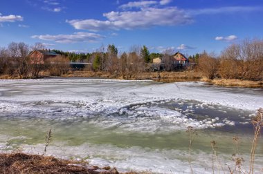 Erken Ilkbahar manzarası, köyün kenarındaki küçük bir nehirde buz eritir.