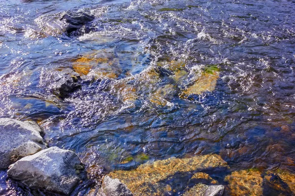 Ρεύματα νερού από έναν ορεινό ποταμό πλύσιμο πέτρες που καλύπτονται με χρωματιστά βρύα. — Φωτογραφία Αρχείου