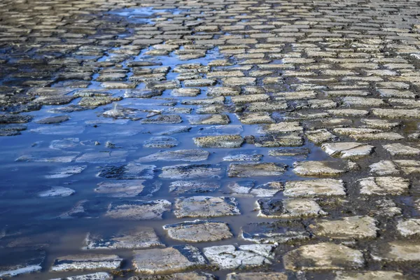 Céu de primavera azul refletido nas poças no pavimento de paralelepípedos . — Fotografia de Stock