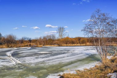Erken Ilkbahar manzarası, köyün kenarındaki küçük bir nehirde buz eritir.