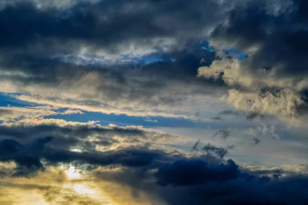 Cielo azul con nubes de oro - puesta de sol dramática, hermoso fondo natural. El sol poniente ilumina las nubes . — Foto de Stock