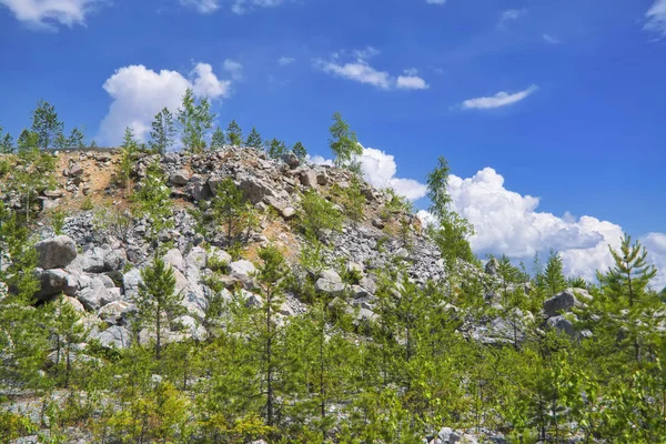 Berghelling met grote stenen tegen een blauwe zomer hemel met witte Cumulus wolken. — Stockfoto