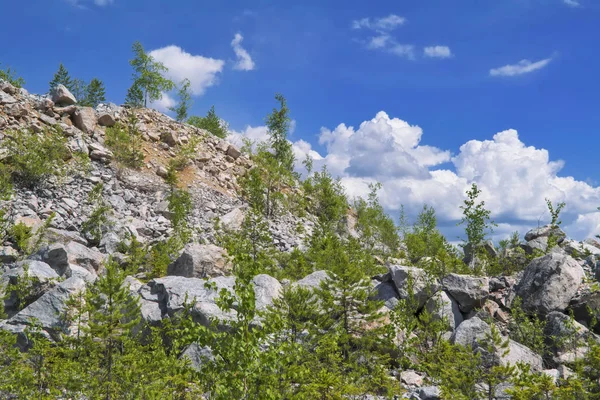 Berghelling met grote stenen tegen een blauwe zomer hemel met witte Cumulus wolken. — Stockfoto