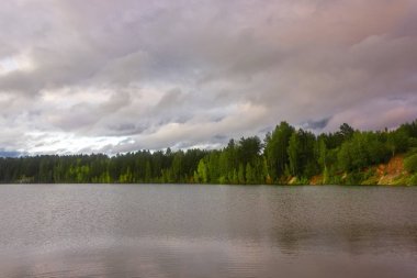 Berrak şeffaf mavi su ile bir orman gölü kıyısında Yaz manzara. Günbatımı.