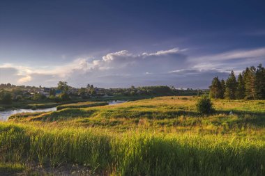 Batan güneşin arka planında nehrin kıyısındaki köy.