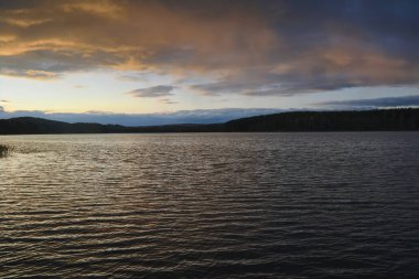 Sonbaharda bir orman gölünün kıyısında güzel bir günbatımı.